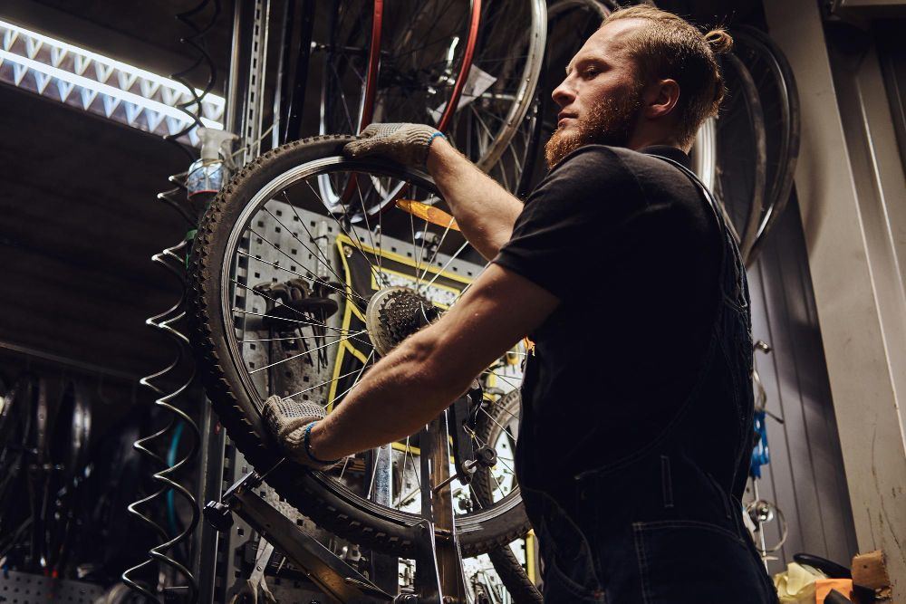 Bike mechanic inspecting a bicycle wheel in a repair workshop