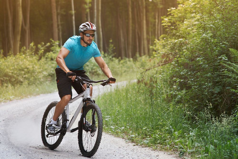 Mountain biker in a helmet riding a gravel forest trail